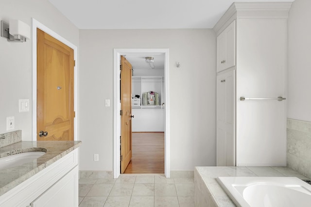 bathroom featuring a relaxing tiled tub, a closet, and vanity