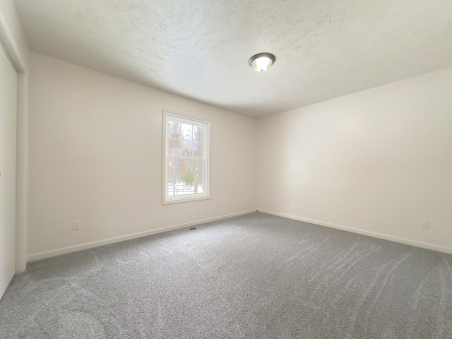 carpeted empty room featuring baseboards, visible vents, and a textured ceiling