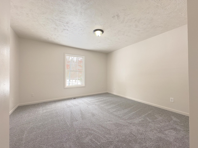 spare room with visible vents, a textured ceiling, baseboards, and carpet flooring