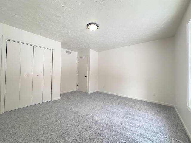 unfurnished bedroom featuring baseboards, carpet, visible vents, and a textured ceiling