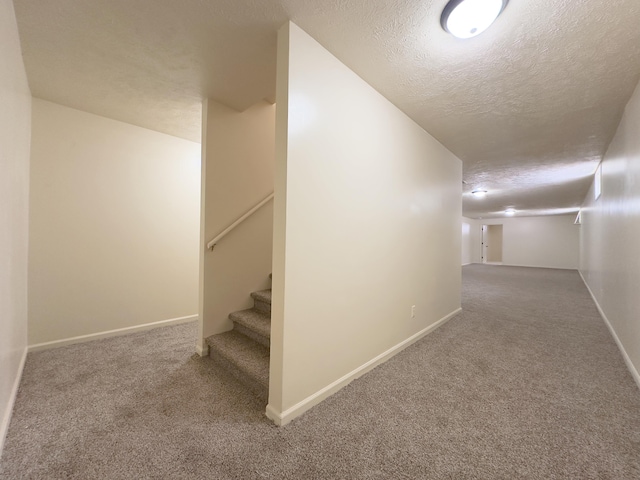 corridor featuring a textured ceiling, stairway, carpet, and baseboards