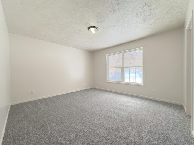 spare room with a textured ceiling, carpet flooring, and baseboards