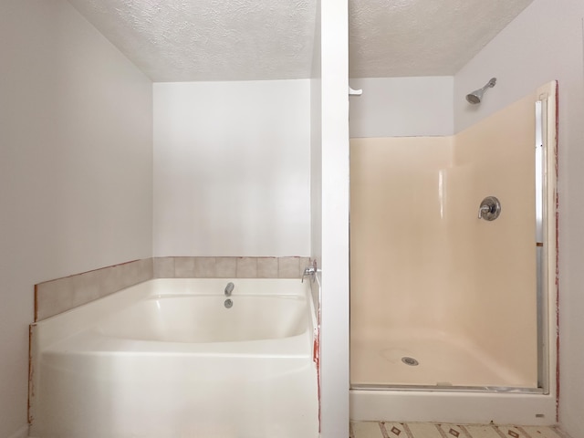 bathroom with a garden tub, walk in shower, and a textured ceiling