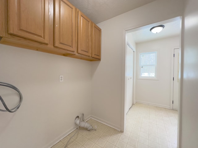 washroom featuring baseboards, cabinet space, a textured ceiling, and light floors