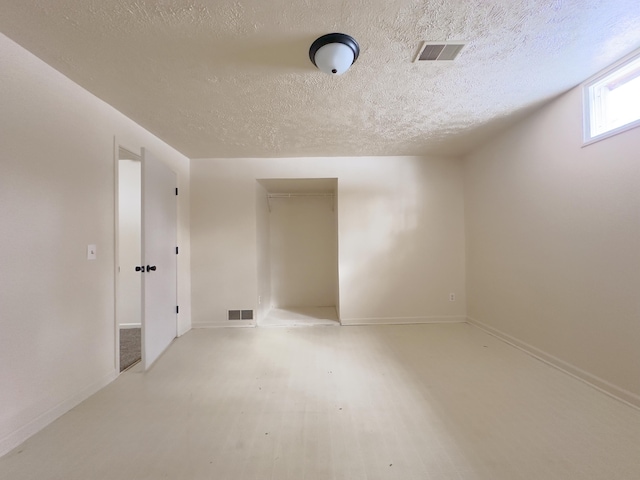 spare room featuring visible vents, a textured ceiling, and light wood finished floors