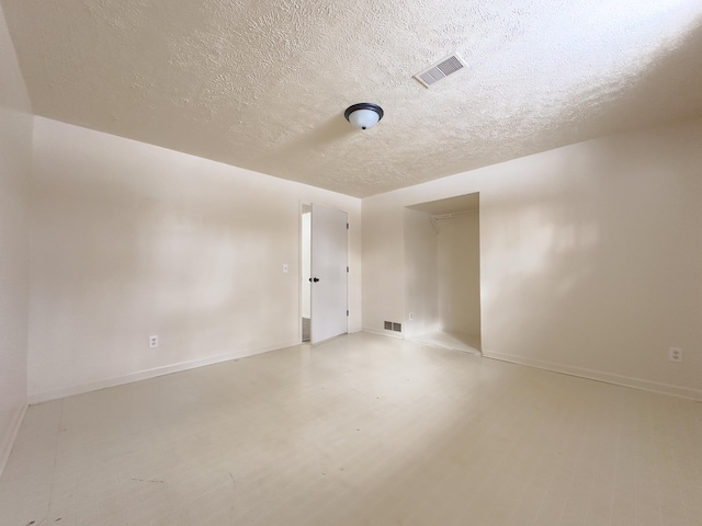 spare room with visible vents, a textured ceiling, and baseboards