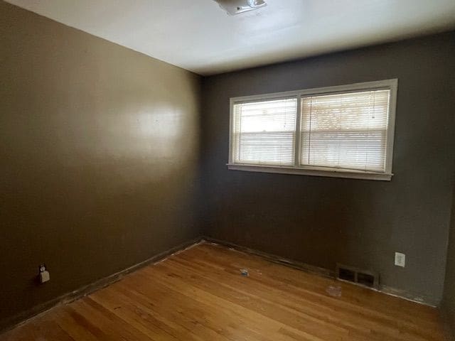 spare room featuring visible vents and wood finished floors