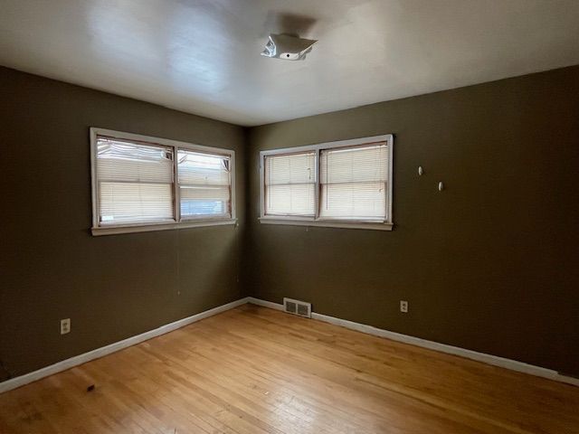 empty room featuring baseboards, visible vents, and wood finished floors