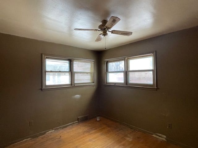 unfurnished room featuring light wood-style floors, ceiling fan, visible vents, and a wealth of natural light