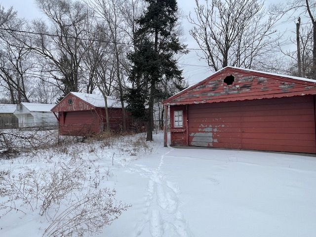 snowy yard featuring a garage and an outdoor structure