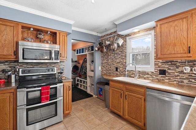 kitchen with light tile patterned flooring, stainless steel appliances, a sink, open shelves, and washer and clothes dryer