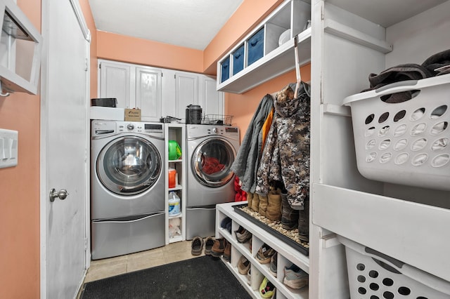 laundry area with cabinet space, independent washer and dryer, and light tile patterned floors