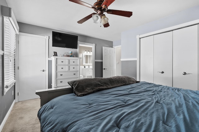 bedroom featuring baseboards, light colored carpet, ensuite bath, ceiling fan, and a closet