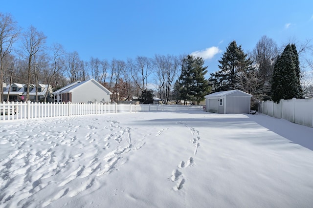 snowy yard featuring a garage, an outbuilding, and fence