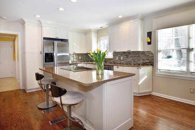 kitchen featuring light stone counters, a kitchen island, white cabinets, backsplash, and dark wood finished floors