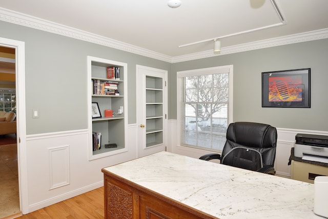 office space with light wood-style floors, wainscoting, built in features, and ornamental molding