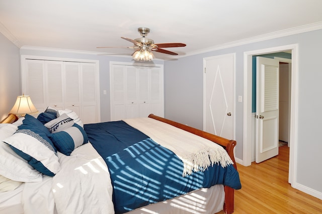 bedroom with crown molding, light wood finished floors, multiple closets, ceiling fan, and baseboards