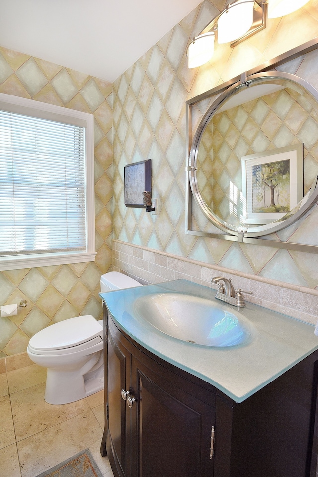 bathroom with toilet, backsplash, tile walls, and vanity