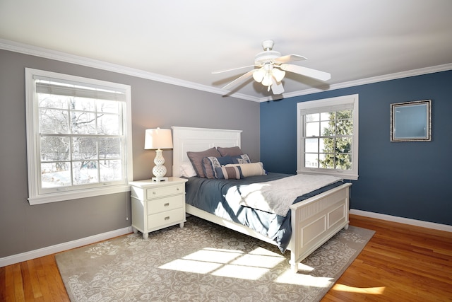 bedroom featuring baseboards, light wood-type flooring, a ceiling fan, and crown molding