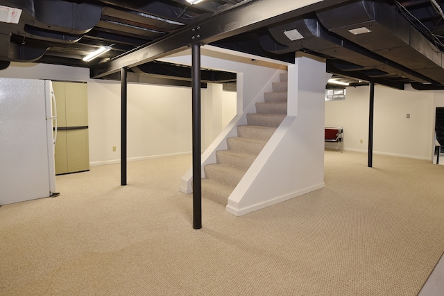 finished basement with light carpet, stairway, baseboards, and freestanding refrigerator