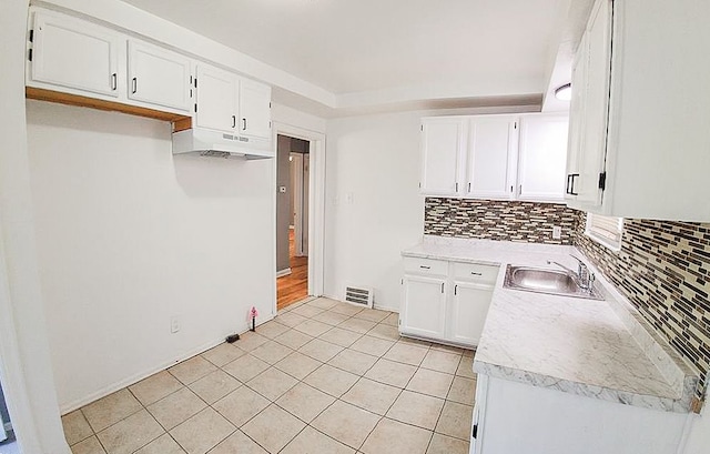 kitchen with a sink, visible vents, white cabinets, light countertops, and backsplash