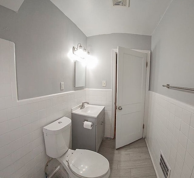 half bathroom featuring visible vents, tile walls, and wainscoting