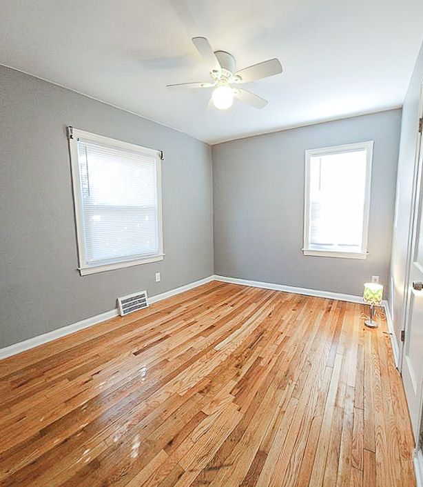 empty room with light wood-style floors, baseboards, visible vents, and a ceiling fan