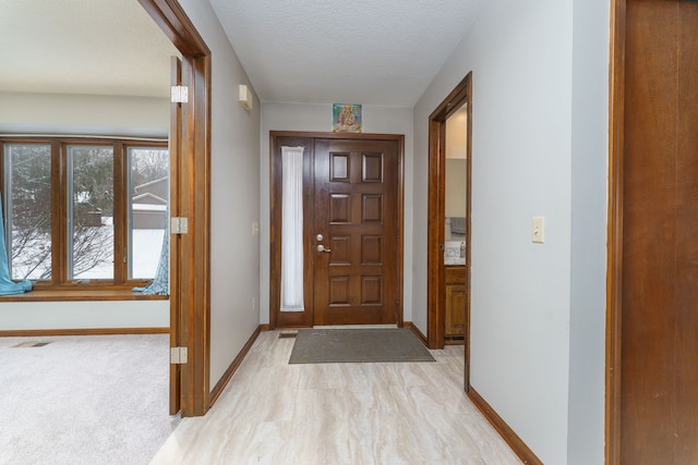 foyer entrance with a textured ceiling and baseboards