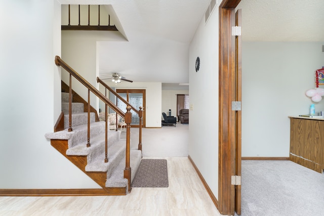 foyer entrance with light carpet, visible vents, baseboards, vaulted ceiling, and stairway