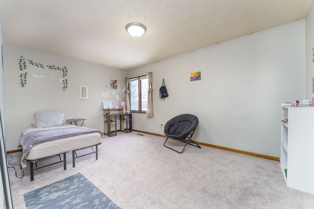 bedroom featuring light carpet, baseboards, and a textured ceiling