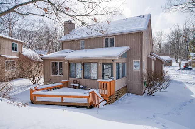 snow covered back of property featuring a chimney