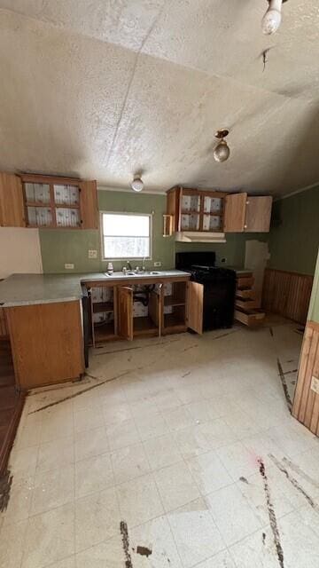 kitchen featuring brown cabinetry, light countertops, glass insert cabinets, and light floors