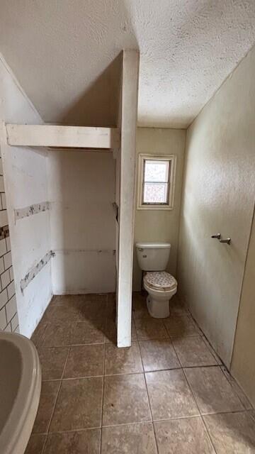 bathroom with toilet, a textured ceiling, and tile patterned floors