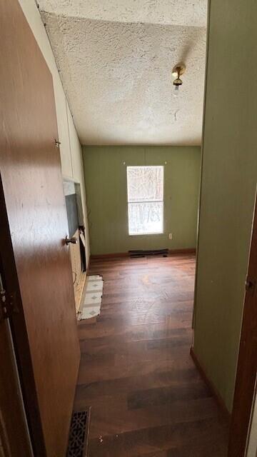 hall with a textured ceiling, baseboards, and wood finished floors