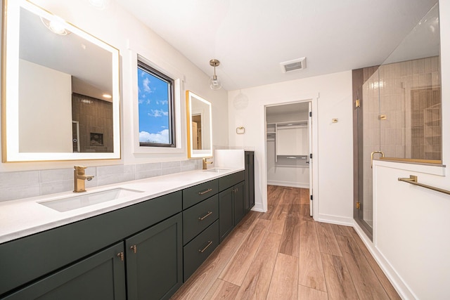 full bath with a spacious closet, visible vents, a sink, and wood finished floors