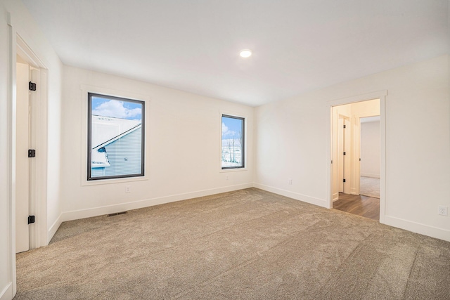 empty room featuring light colored carpet and baseboards