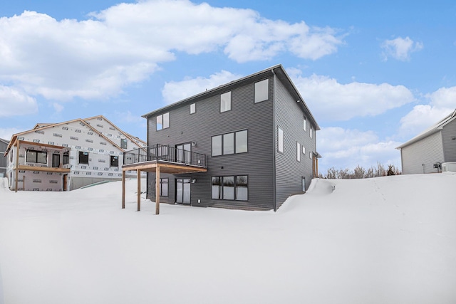 snow covered rear of property with a deck