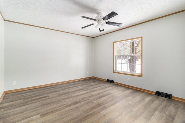 empty room with ornamental molding, light wood finished floors, a textured ceiling, and visible vents