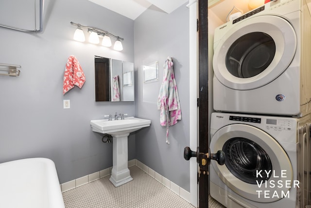 bathroom featuring tile patterned flooring, baseboards, and stacked washing maching and dryer