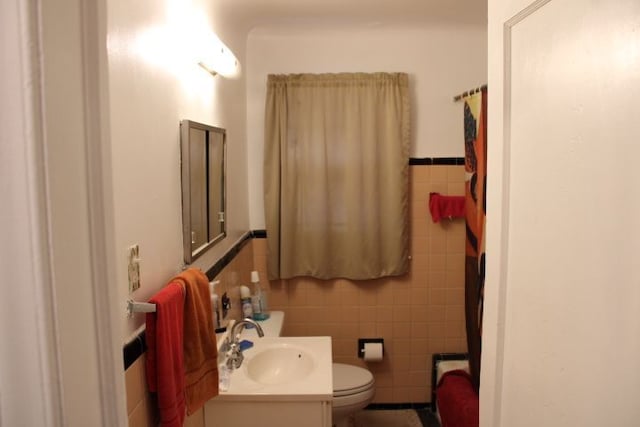 full bath with toilet, a wainscoted wall, vanity, and tile walls