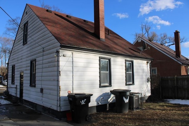 back of house featuring a chimney and fence