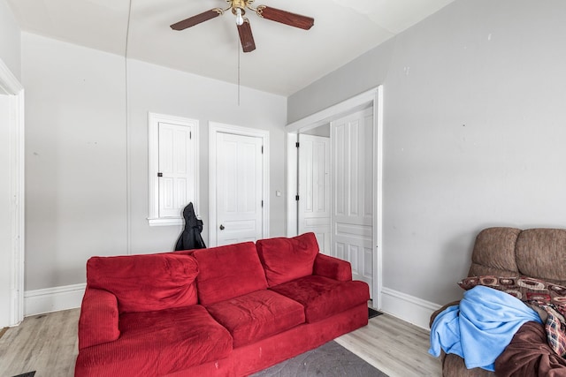 living room featuring light wood finished floors, a ceiling fan, and baseboards