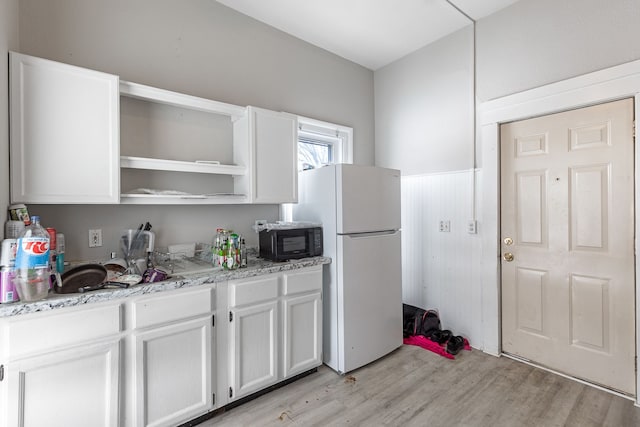 kitchen with freestanding refrigerator, black microwave, white cabinets, and open shelves