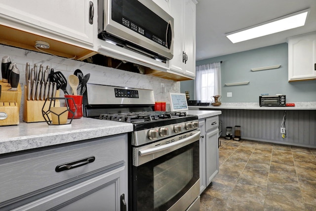 kitchen with stainless steel appliances, white cabinets, light countertops, and decorative backsplash