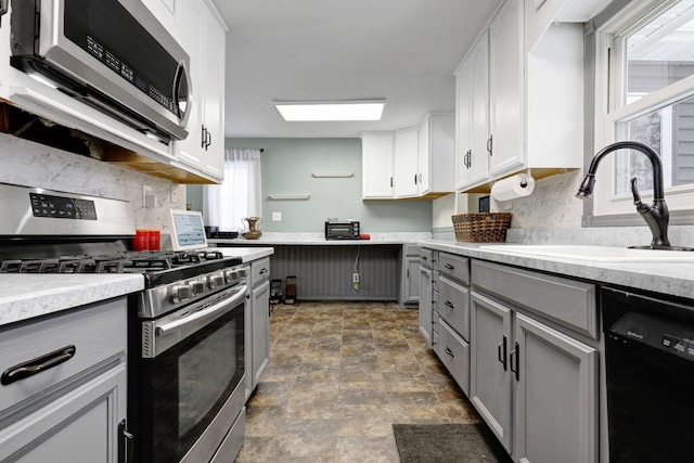 kitchen featuring appliances with stainless steel finishes, gray cabinets, light countertops, and white cabinetry