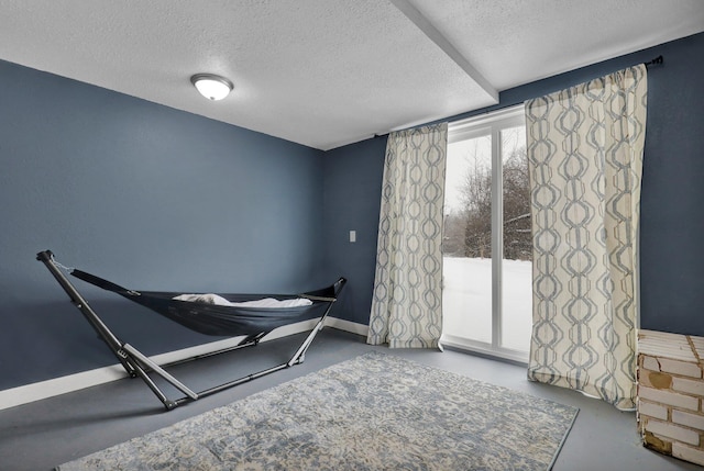 sitting room featuring concrete floors, a textured ceiling, and baseboards