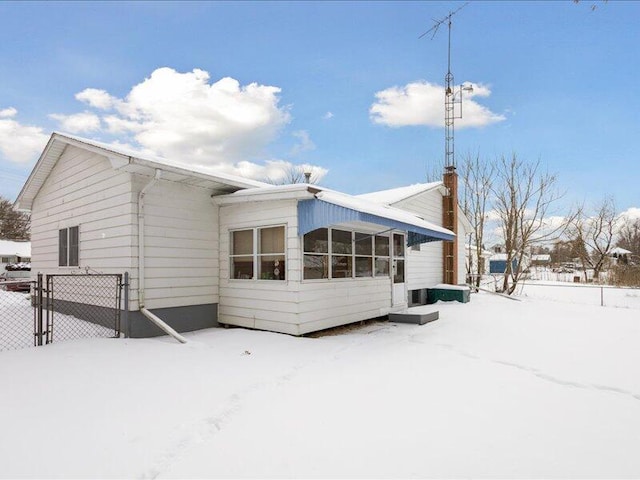 snow covered rear of property featuring fence