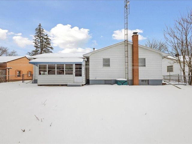 snow covered property featuring a chimney and fence