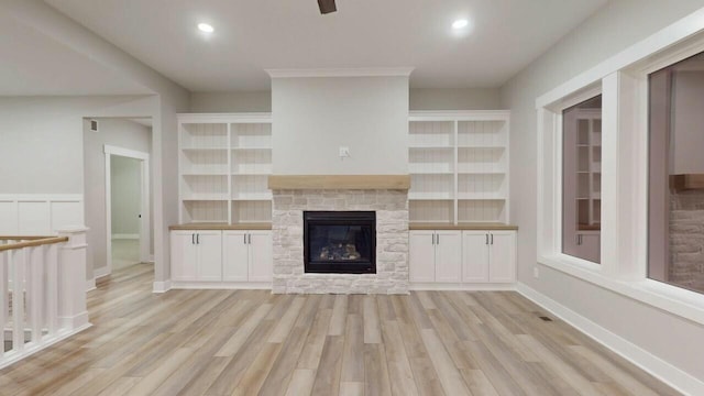 unfurnished living room with baseboards, a stone fireplace, recessed lighting, and light wood-style floors