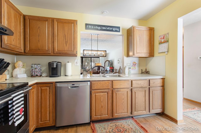 kitchen with a sink, light wood finished floors, stainless steel appliances, and light countertops